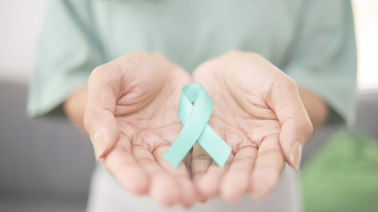 Photo of hands holding light teal cancer ribbon
